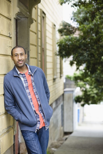 African American man leaning against side of building