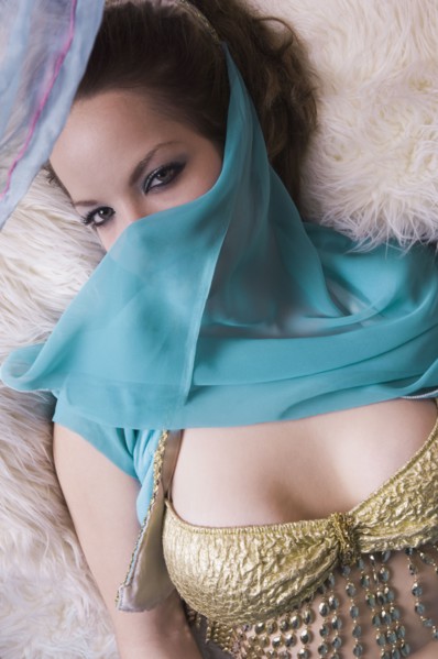 Woman wearing belly dancing outfit with veil and laying down