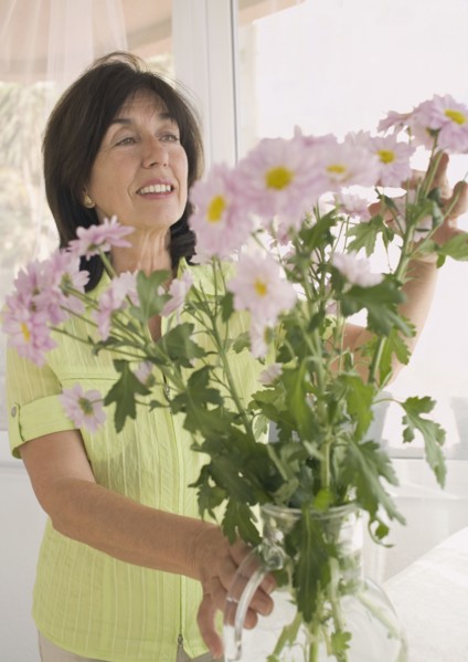Senior woman arranging flowers in vase