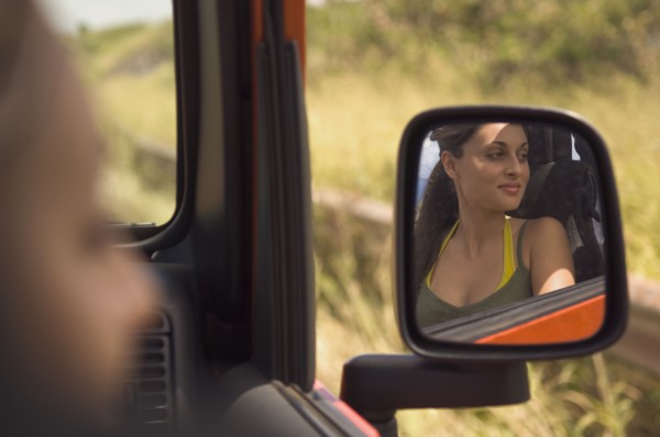 Reflection of Hispanic woman in side mirror of jeep