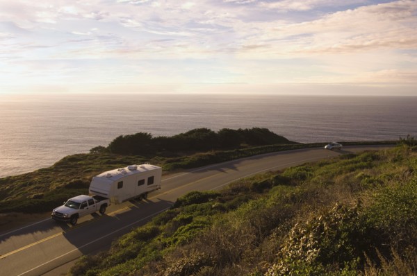 Truck pulling camper on coastal highway