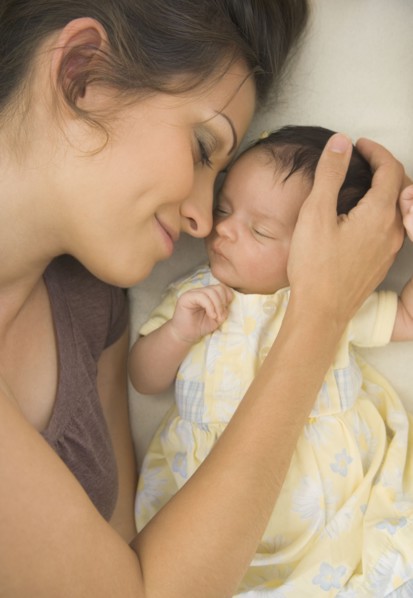 Hispanic mother laying next to baby