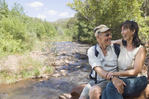 Multi-ethnic senior couple hugging next to stream