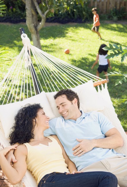 Couple in hammock with children playing in background