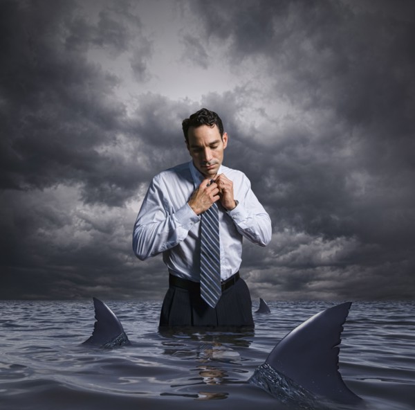 Latin businessman standing in shark infested waters