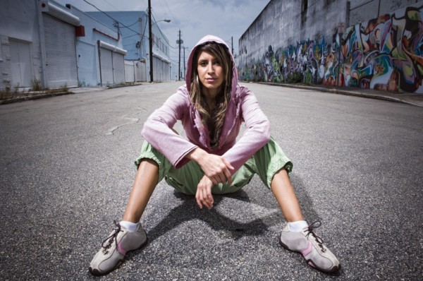 Hispanic woman sitting in alley with graffiti