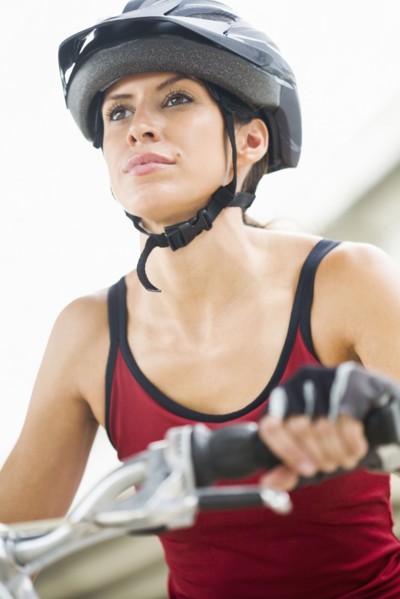 Hispanic woman in helmet riding bicycle