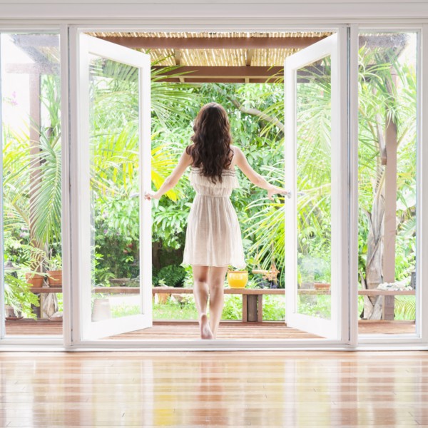Hispanic woman opening French doors to patio