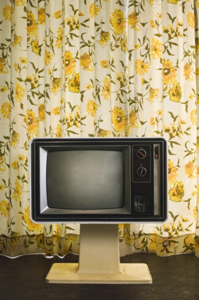 Old-fashioned television near floral curtain