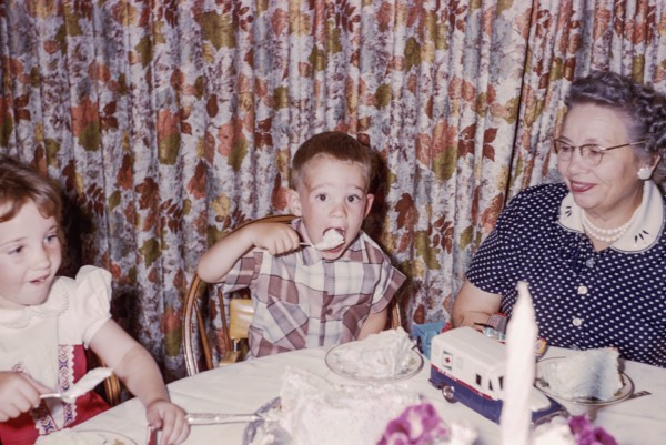 Caucasian woman watching grandson and granddaughter eating cake