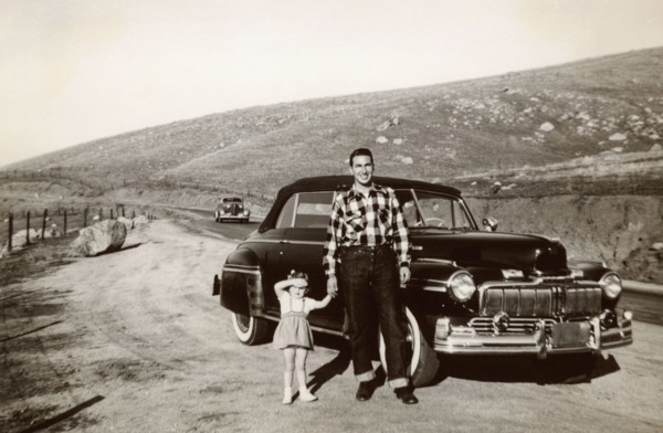 Portrait of Caucasian father and daughter posing near vintage car