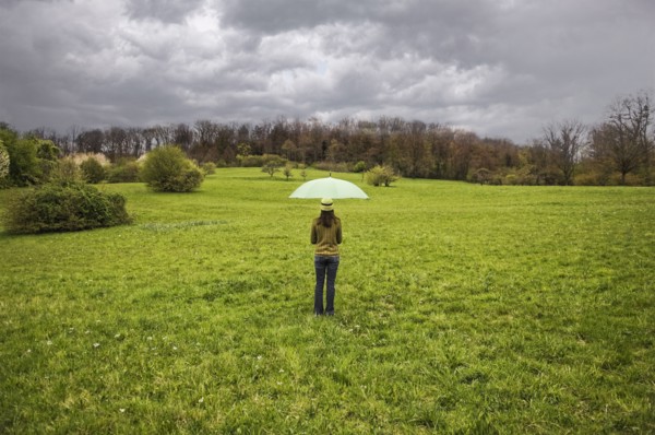 Mixed Race holding umbrella in field