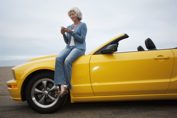 Caucasian woman sitting on convertible at beach