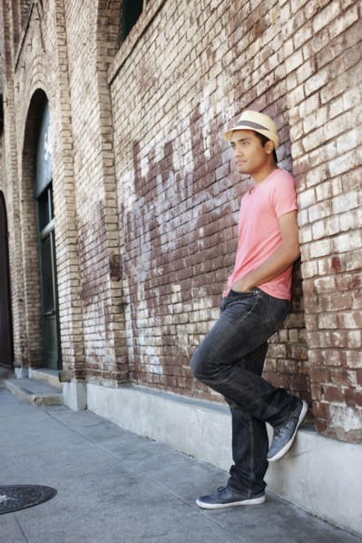 Asian man leaning against brick wall