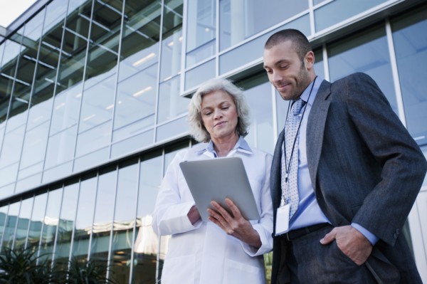 Doctor and businessman using digital tablet outdoors