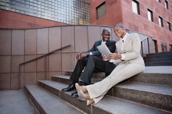 Business people sitting in stairs using digital tablet