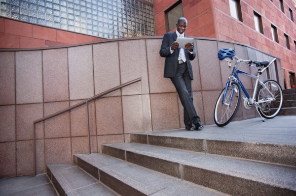 Businessman standing near bicycle using digital tablet