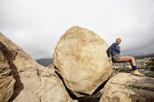 Black woman pushing large rock