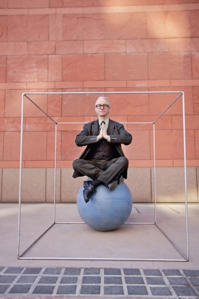 Caucasian businessman practicing yoga on ball inside of box