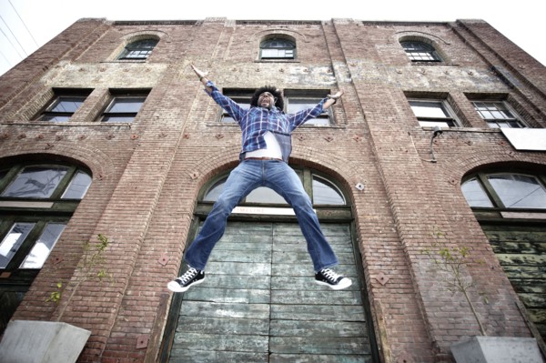 Black man jumping next to urban building