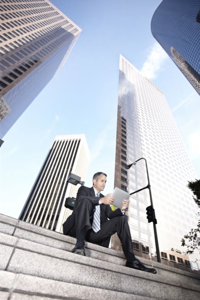 Hispanic businessman sitting on steps with digital tablet