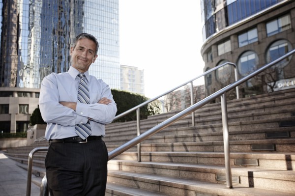 Hispanic businessman standing outdoors with arms crossed