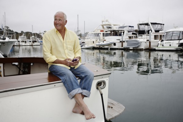 Man sitting on boat text messaging on cell phone