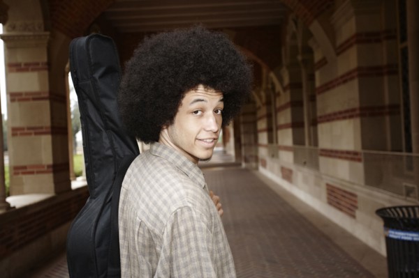 Man with afro carrying guitar in case