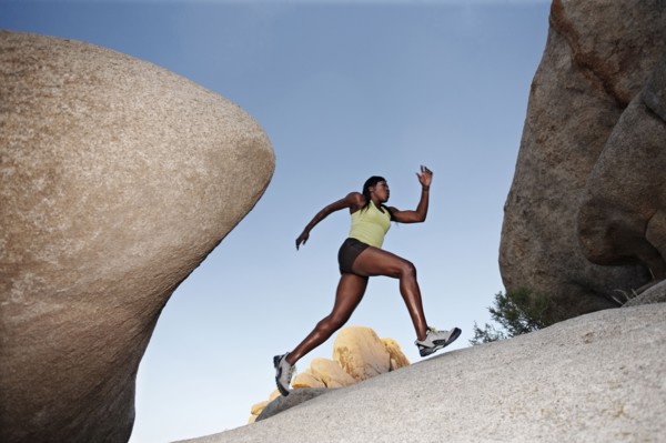 Woman running up boulder in remote area