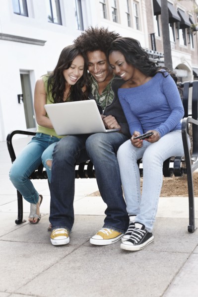 Friends sitting on bench using laptop