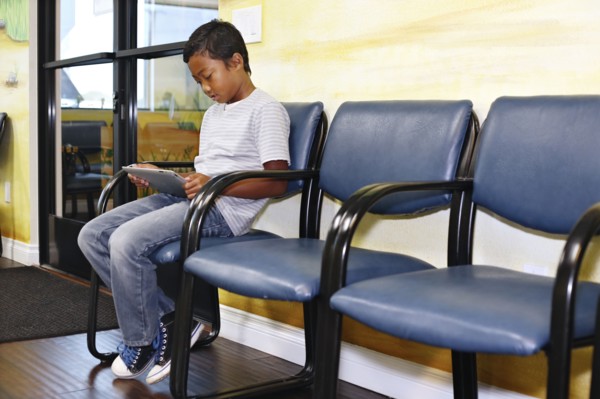Mixed race boy using digital tablet in waiting room