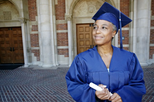 Smiling Black woman holding graduation diploma