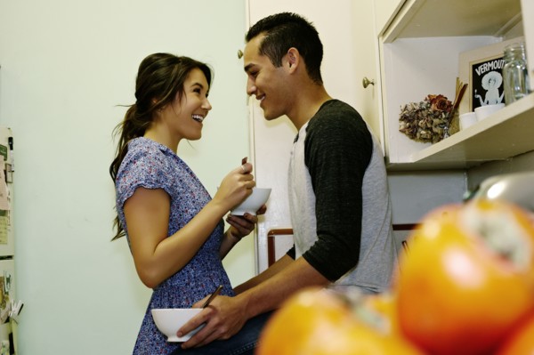 Smiling couple eating cereal in kitchen