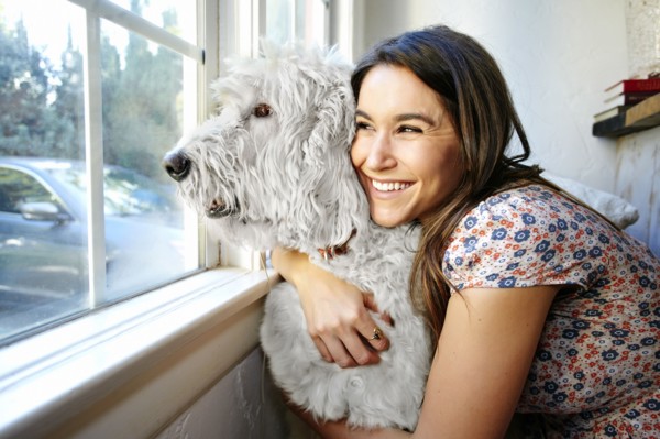 Caucasian woman hugging dog at window