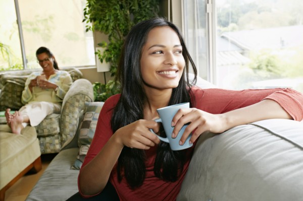 Indian woman having cup of coffee on sofa
