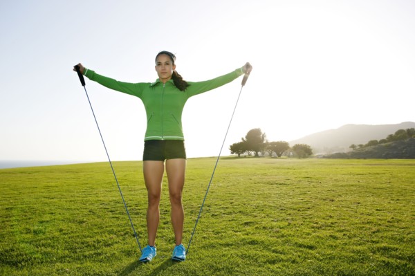 Hispanic woman jumping rope in rural landscape