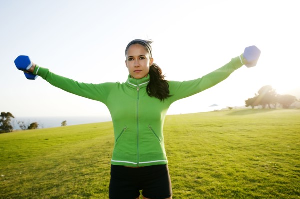 Hispanic woman lifting weights in field