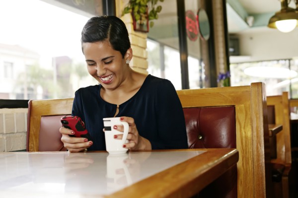 Hispanic businesswoman using cell phone in restaurant