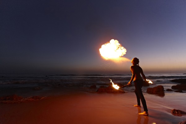 Woman breathing fire on beach