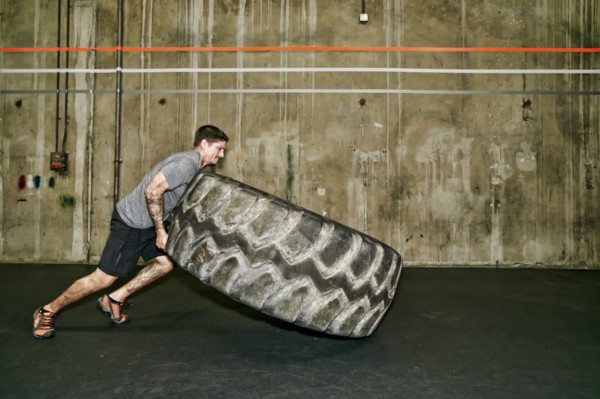 Caucasian man lifting large tire in gym