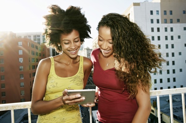 Mixed race women using digital tablet on urban rooftop