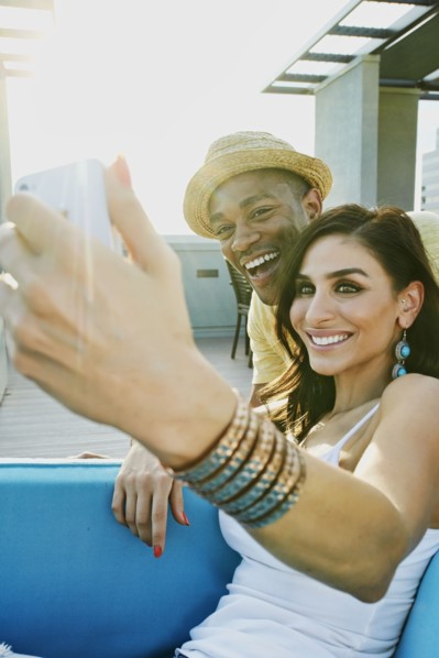 Couple taking self-portrait on sofa on balcony