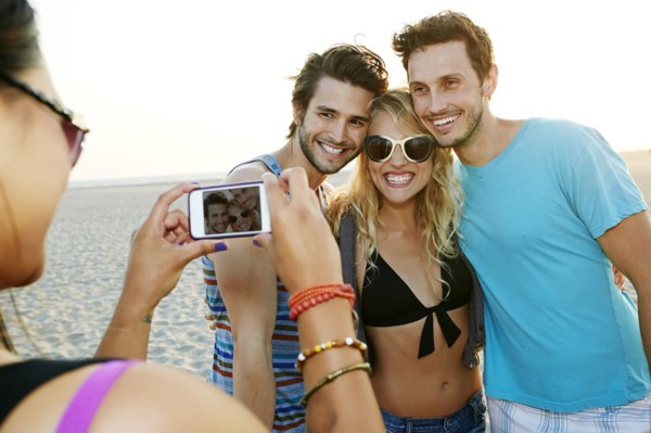 Friends taking pictures together on beach