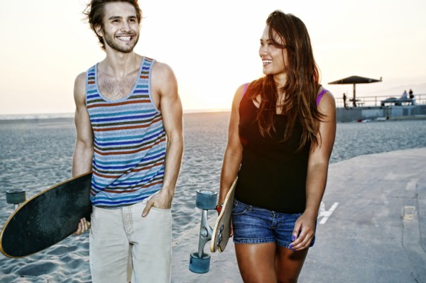 Couple carrying skateboards on beach