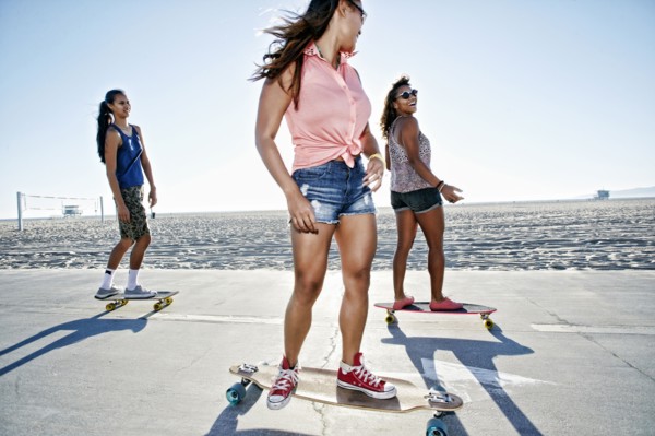 Friends riding longboards on beach
