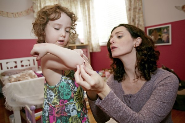 Caucasian mother examining daughter's scrape