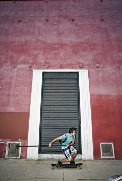 Caucasian man riding skateboard with land paddle