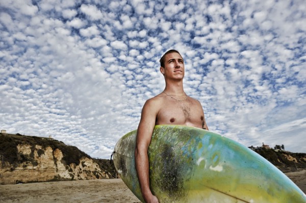 Caucasian man carrying surfboard on beach