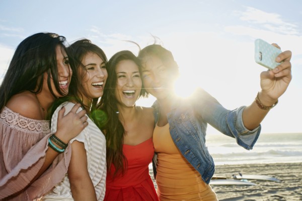 Women taking pictures together on beach