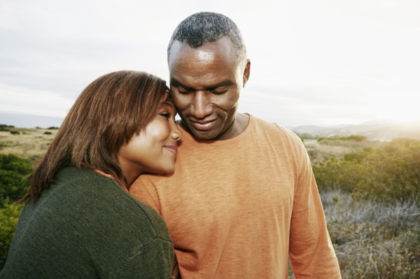 Black couple hugging on rural hillside